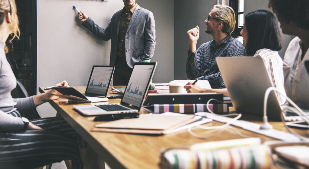 Equipe de consultoria empresarial em reunião de planejamento estratégico em Ribeirão Preto, analisando dados e metas em notebooks.