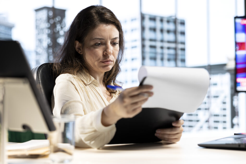 Empresária em escritório analisando contrato para gestão de dívidas bancárias e renegociação de passivos.